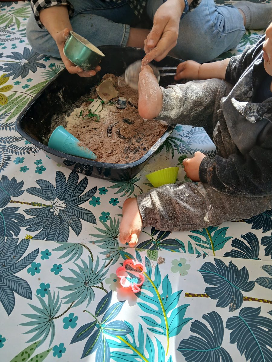 Enfants et parents autour d’un bac sensoriel lors d’un atelier À 4 mains